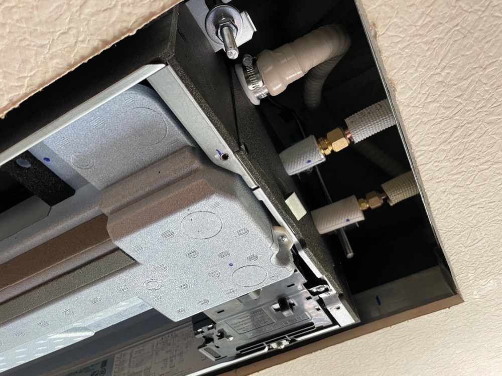 新しい天井埋込カセット形室内機へ冷媒配管を接続している作業
